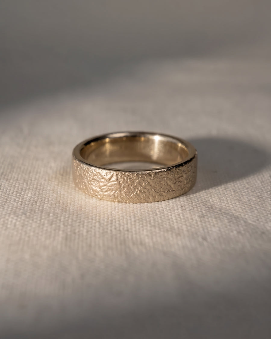 4mm 9ct white gold wedding ring with a textured, organic surface resting on a light fabric background.