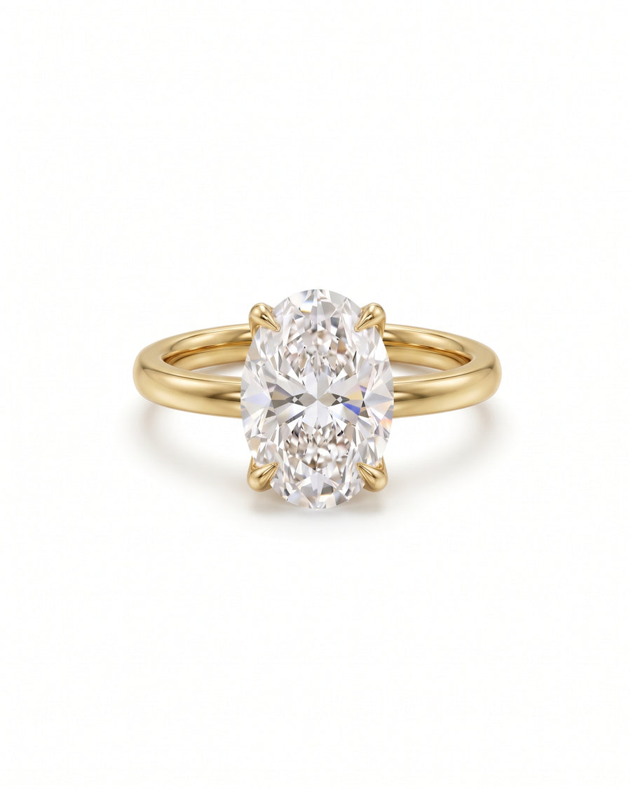 Oval solitaire engagement ring with a clear gemstone set in a polished yellow gold band.