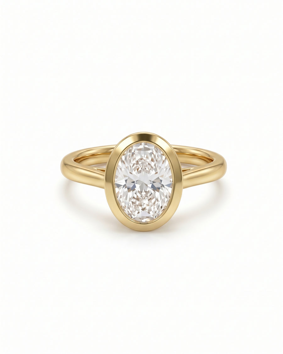 Oval cut diamond engagement ring in a yellow gold bezel setting with a cathedral band.