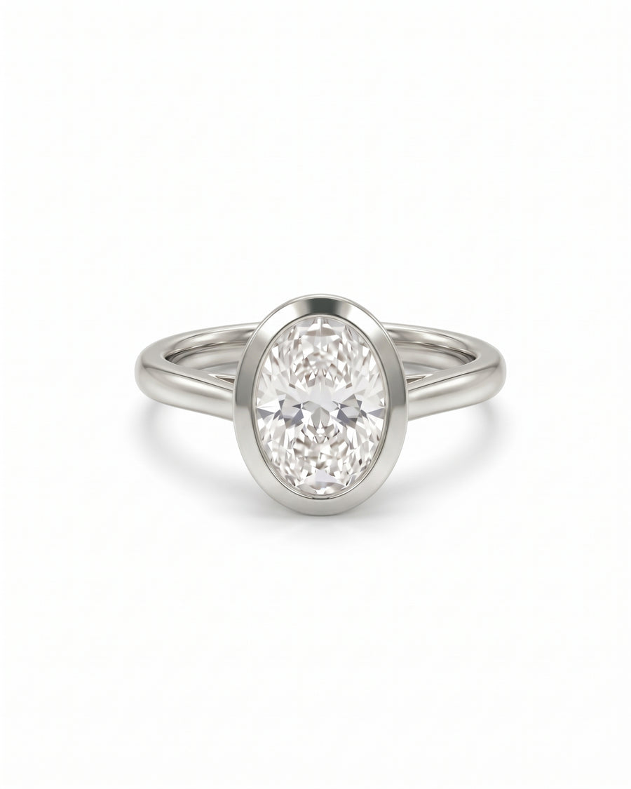 Oval cut diamond engagement ring with a silver bezel setting and a cathedral band on a white background.