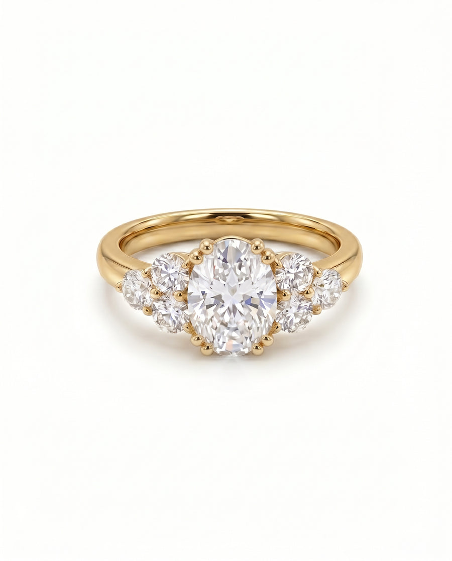 Oval cut diamond engagement ring with trefoil claw settings on a yellow gold band.