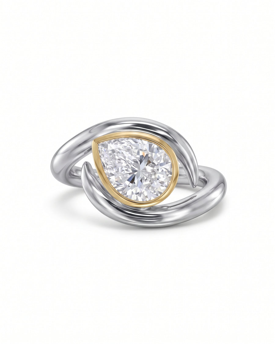 Pear cut diamond engagement ring with a gold bezel setting on a silver spiky bypass band.