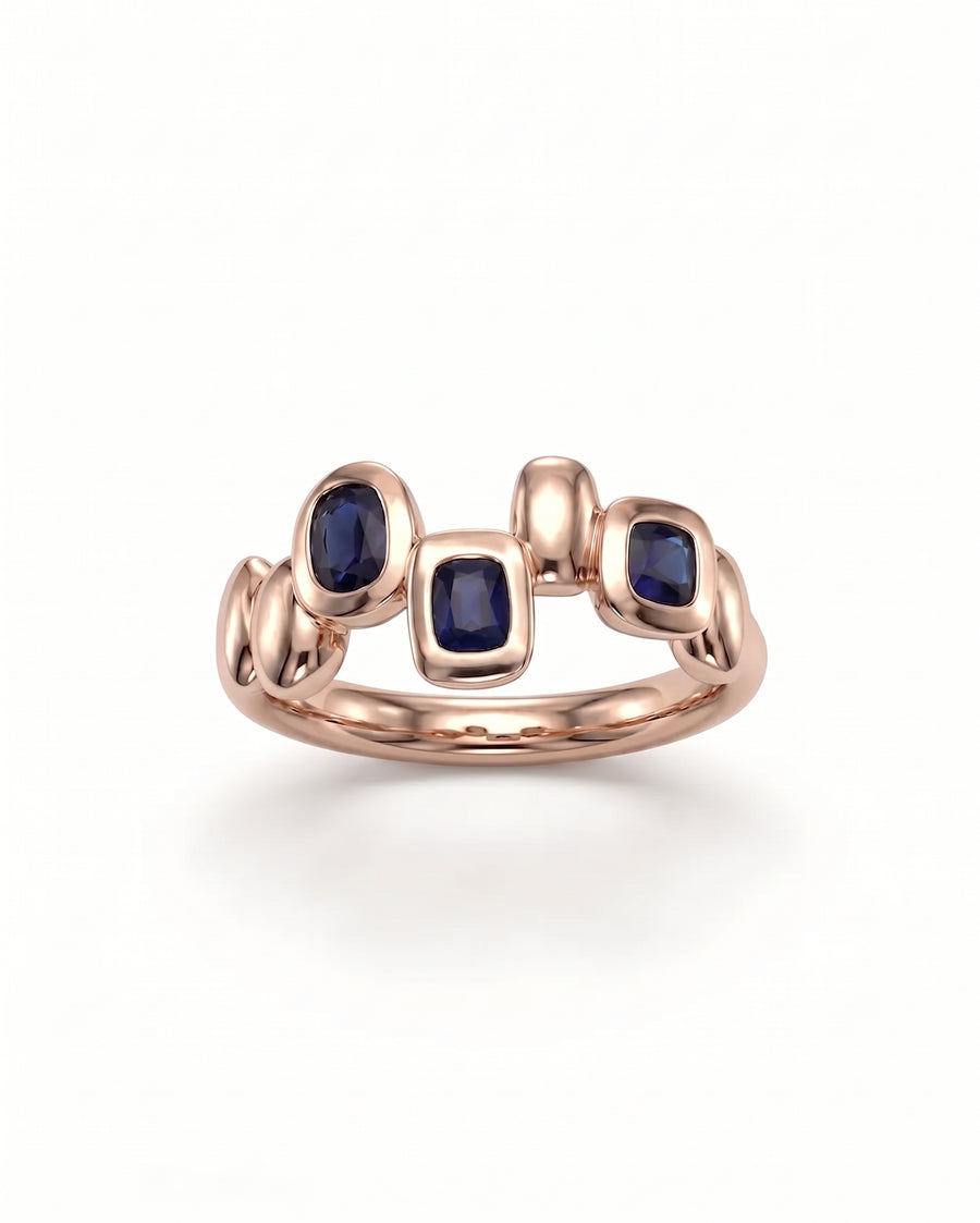 Rose gold eternity ring featuring three bezel-set blue sapphire pebbles in an organic, rounded design.
