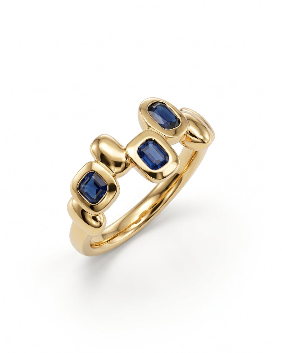 Gold eternity ring featuring three rectangular blue sapphire gemstones set in smooth, pebble-shaped metal links.