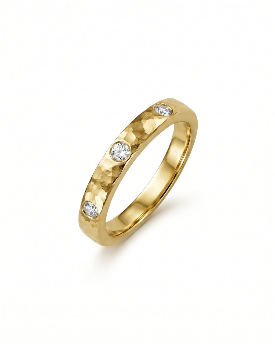 Gold band ring with a hammered texture and three flush-set round diamonds.