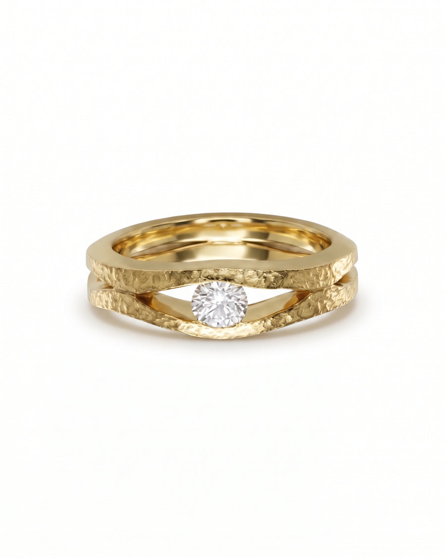 Gold solitaire ring with a hammered texture and a round diamond set between two split bands.