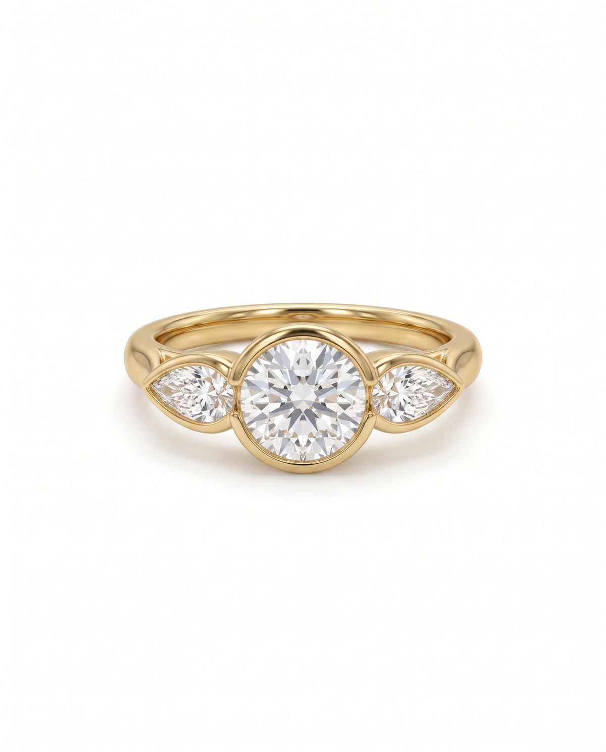 Gold trilogy engagement ring with a round brilliant center diamond and two pear shaped side diamonds in bezel settings.