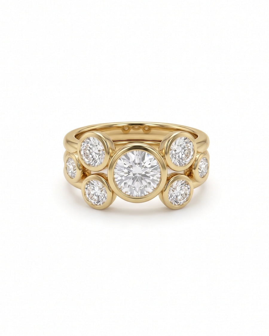 Gold stacking engagement ring featuring a large center round cut diamond surrounded by smaller bezel-set diamonds.