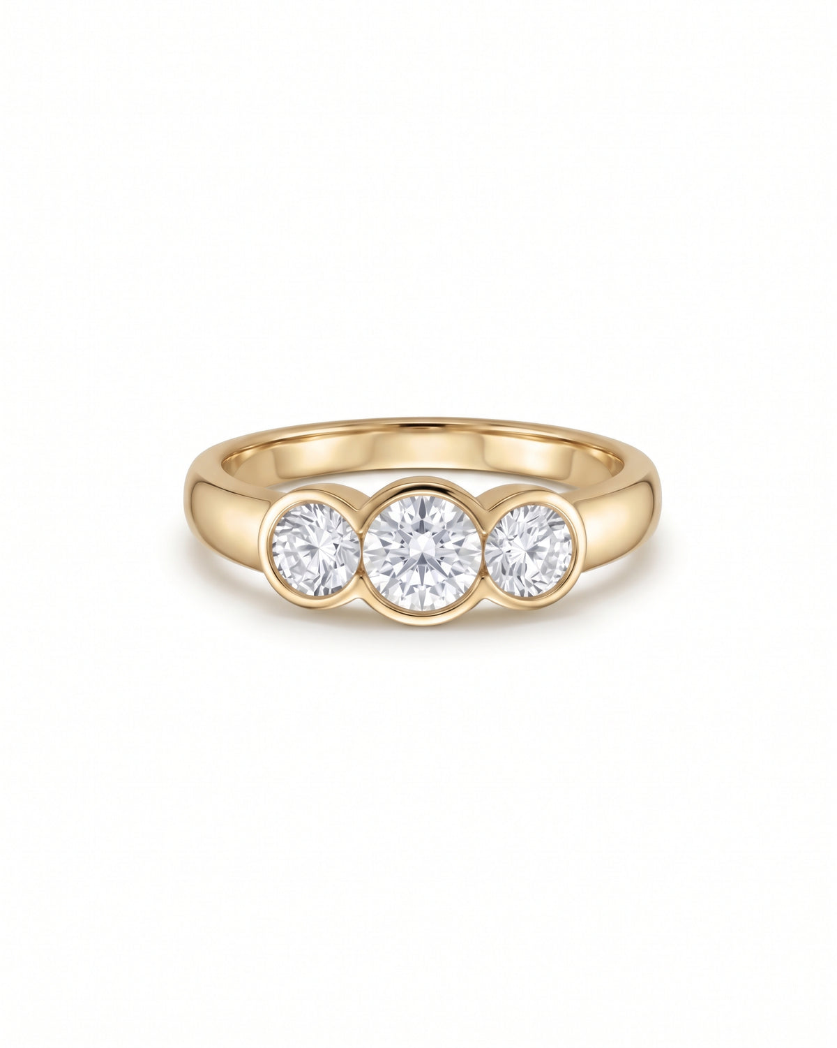 Yellow gold trilogy engagement ring featuring three bezel-set round cut diamonds.