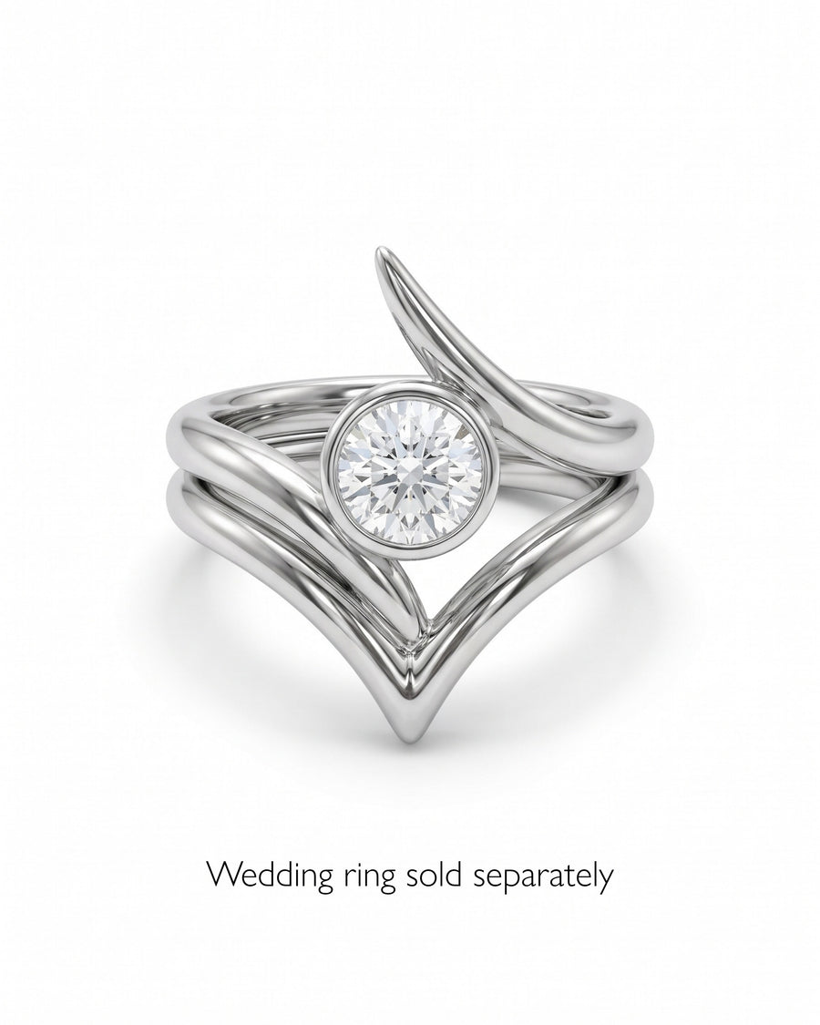 Silver engagement ring with a round bezel-set diamond and a curved, spiky V-shaped band design.