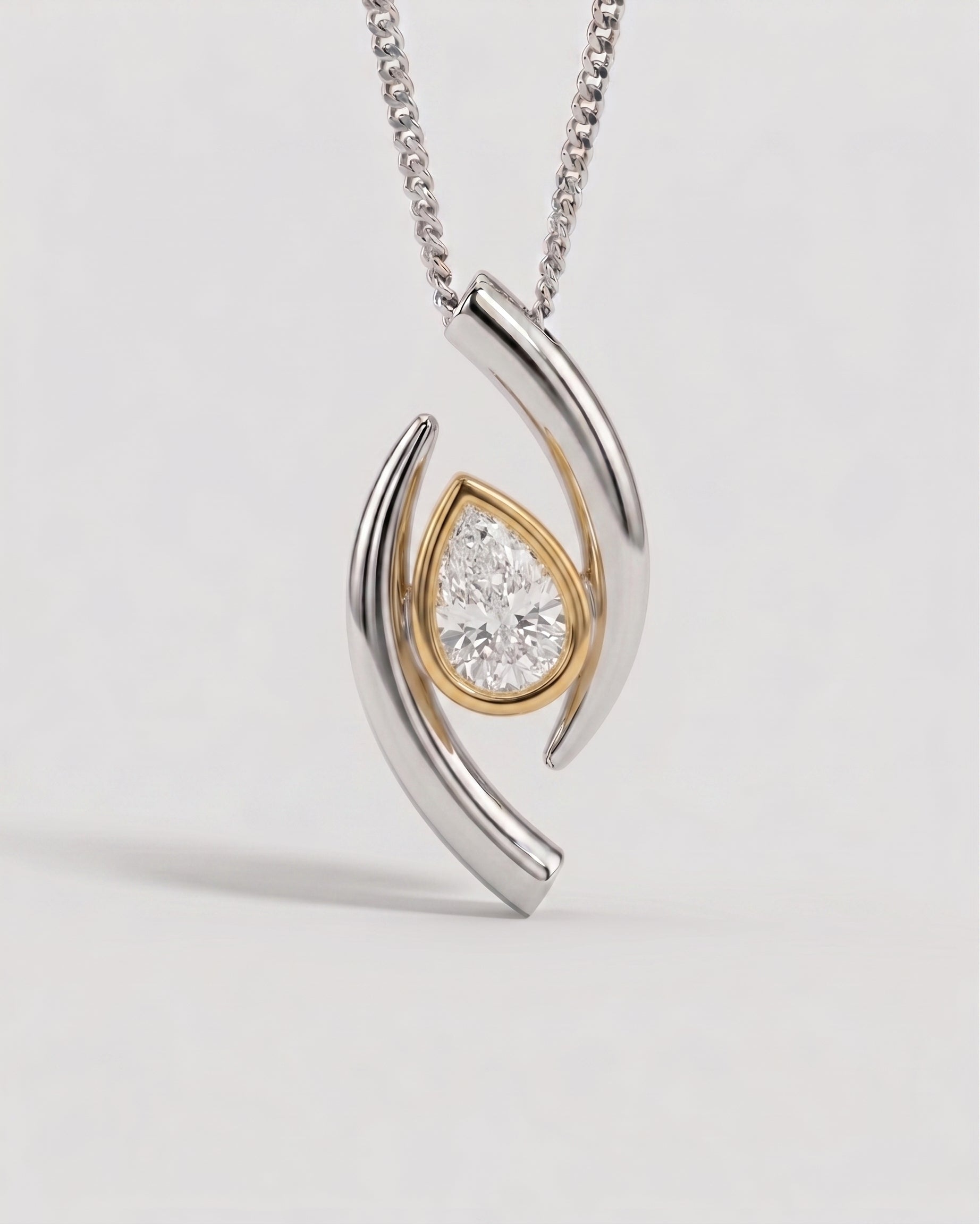 Pear-shaped diamond pendant in a two-tone gold and silver curved setting on a matching chain.