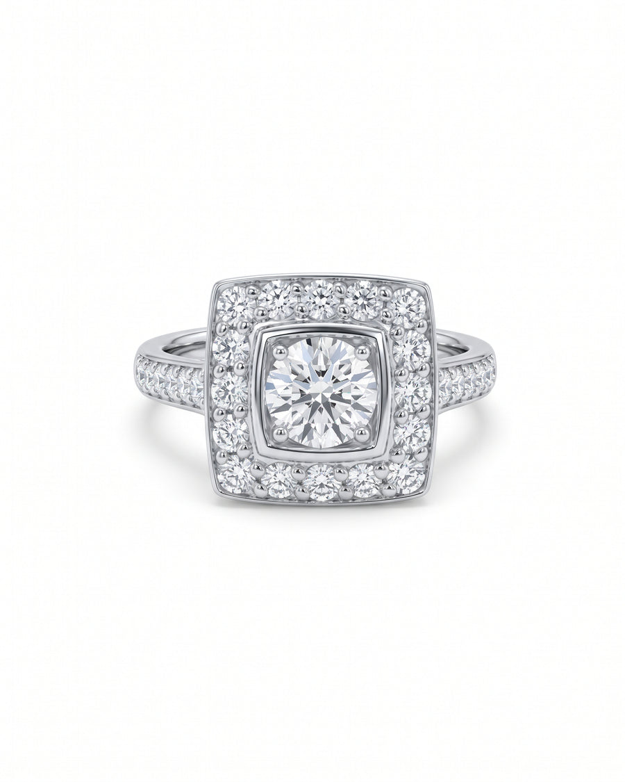 Square cluster engagement ring in white gold with a round center diamond and pavé diamond shoulders.