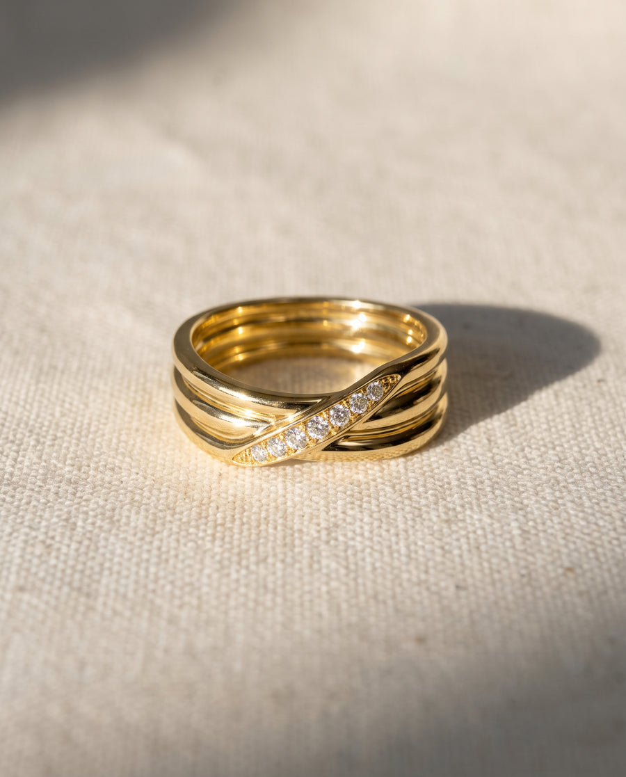 9ct yellow gold three-strand crossover ring featuring a row of small round diamonds set on a textured surface.