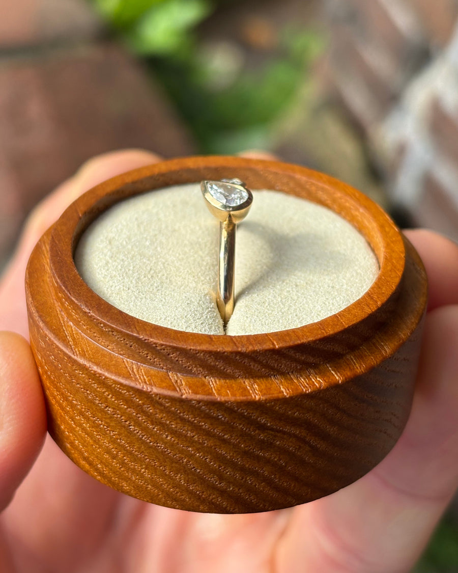 Gold toi et moi engagement ring with two bezel-set pear-shaped diamonds in a wooden ring box.