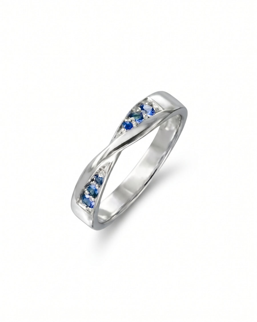Silver twist ring featuring small blue sapphire gemstones set into the band.