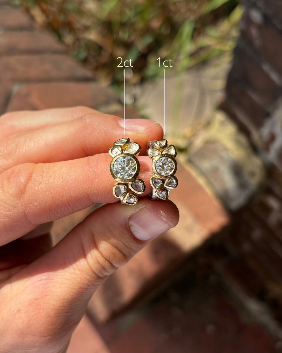 Two-tone gold stacking rings featuring round brilliant and rough diamonds held between fingers.