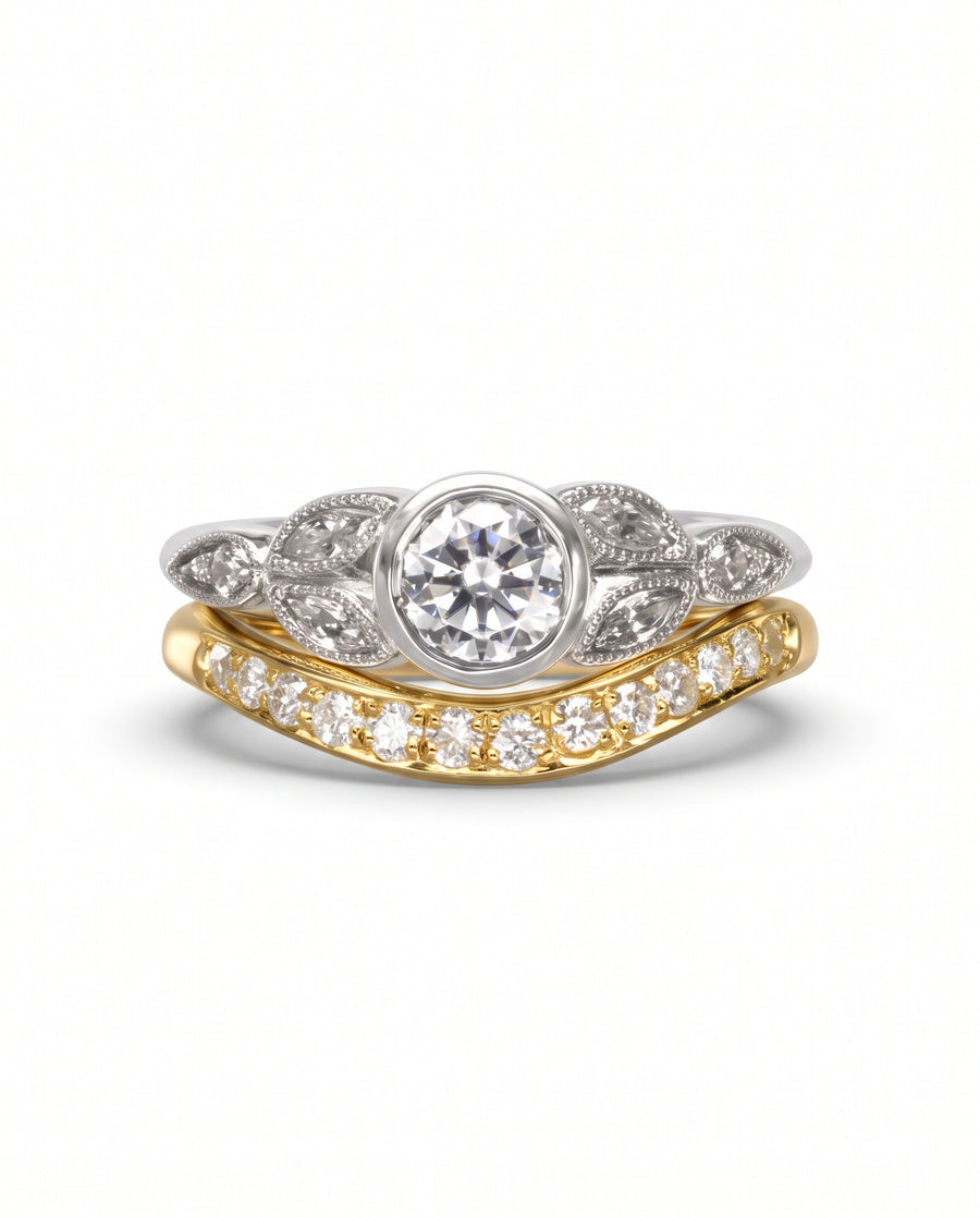 Bezel set diamond engagement ring with a leaf-inspired white gold band and a curved yellow gold diamond band.