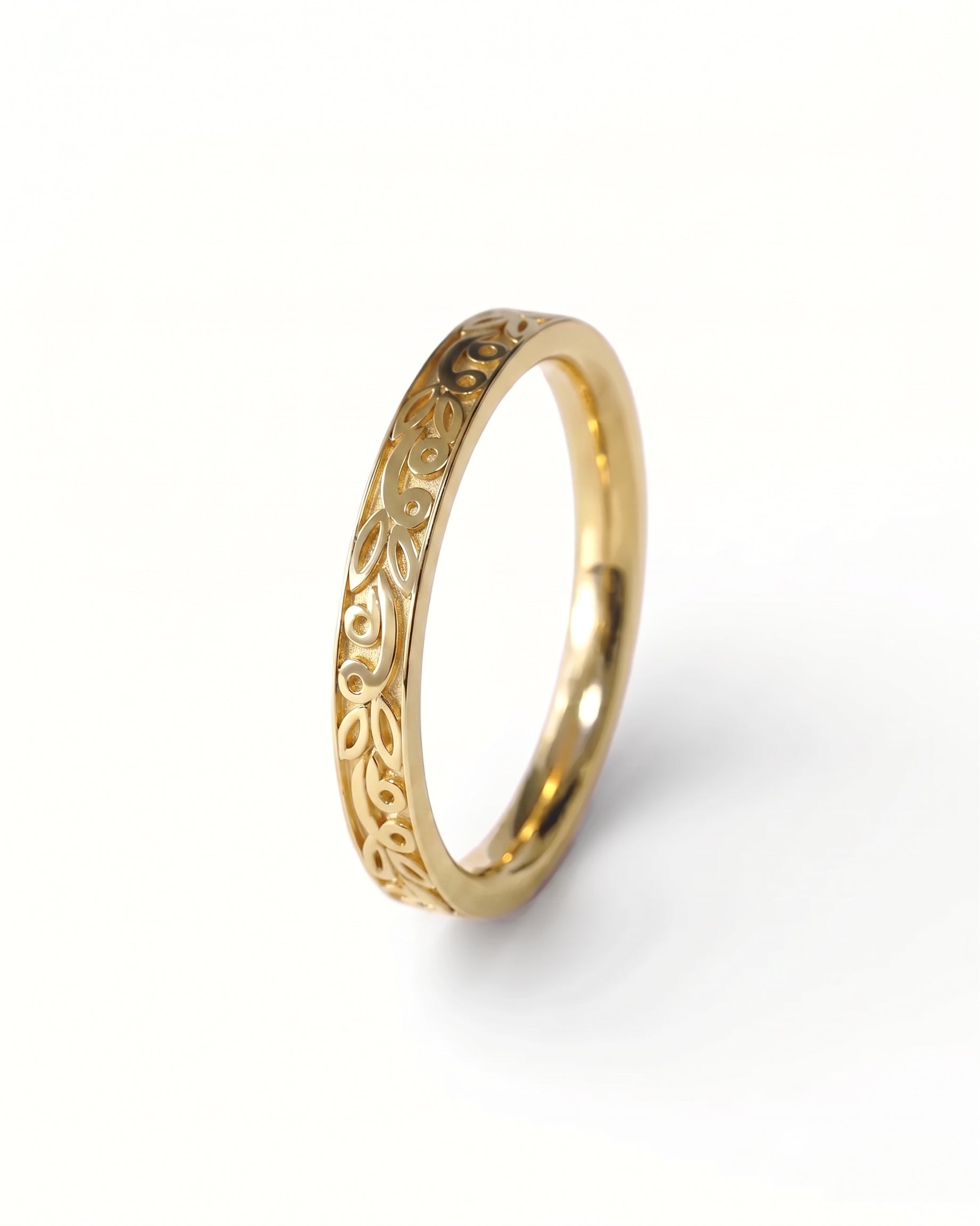 Gold wedding ring with a polished finish and intricate carved leaf patterns along the band.
