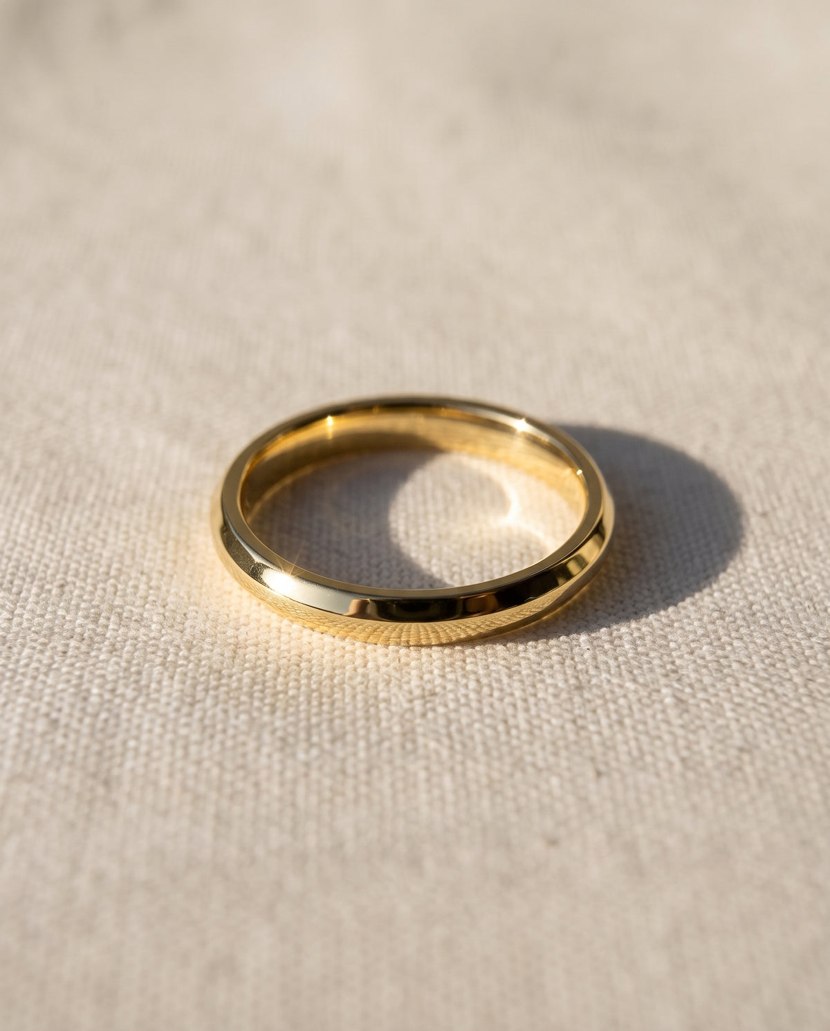 2mm wedding band in 9ct yellow gold with a polished, smooth domed design on a textured fabric background.