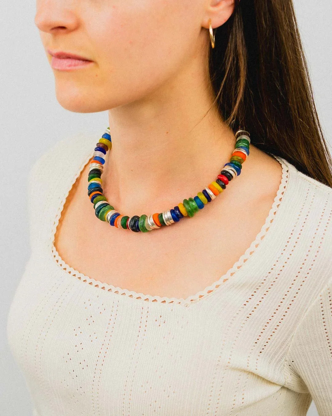 Woman wearing a colorful recycled glass bead necklace with organic, chunky shapes.