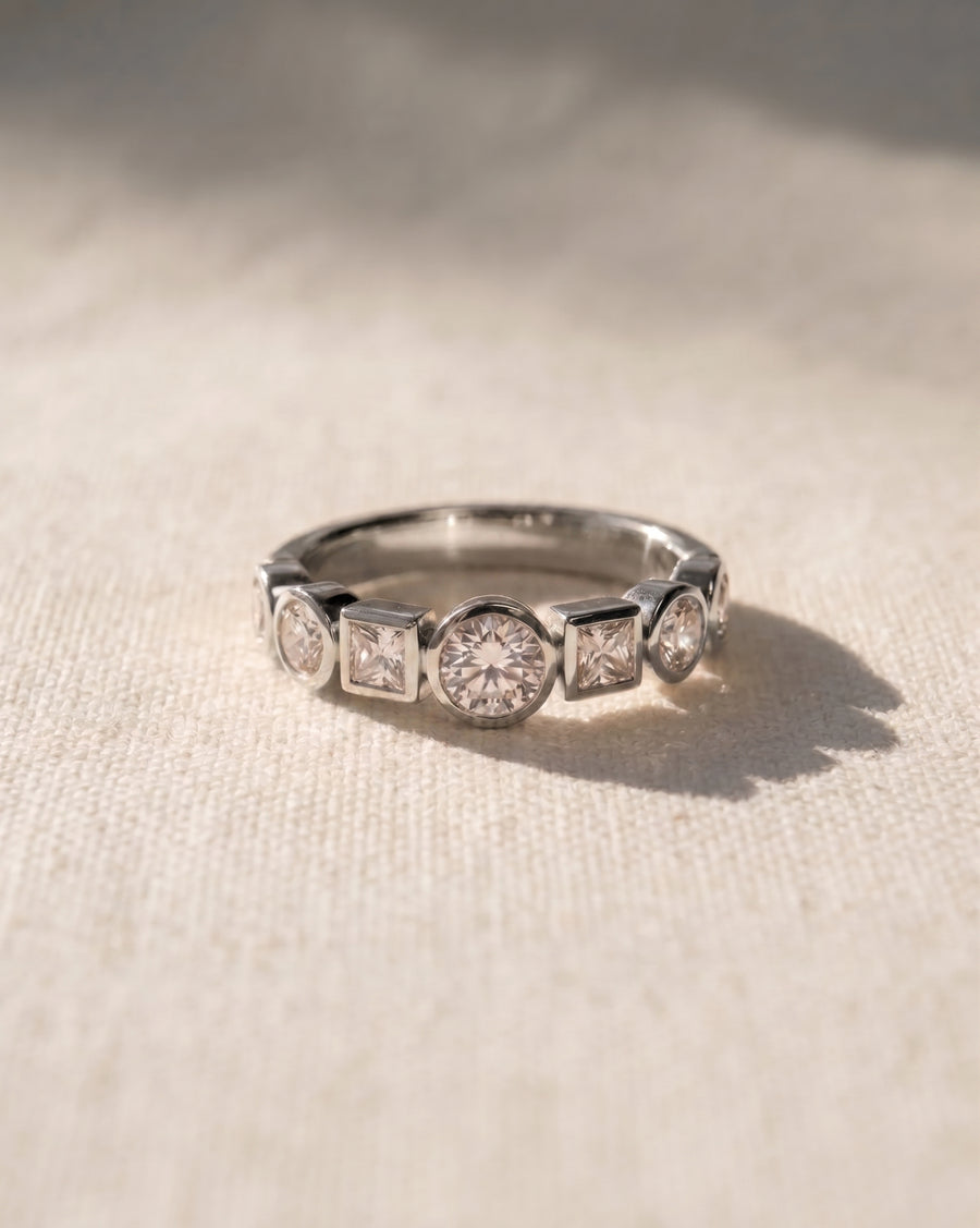 Platinum half eternity ring with alternating round and square diamonds.