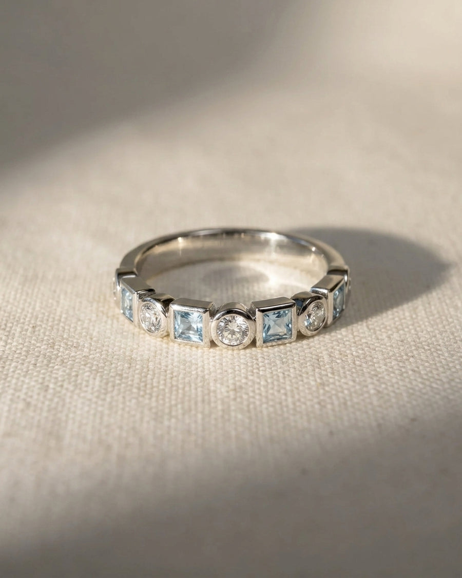 Platinum half eternity ring with alternating aquamarine and diamond gemstones.