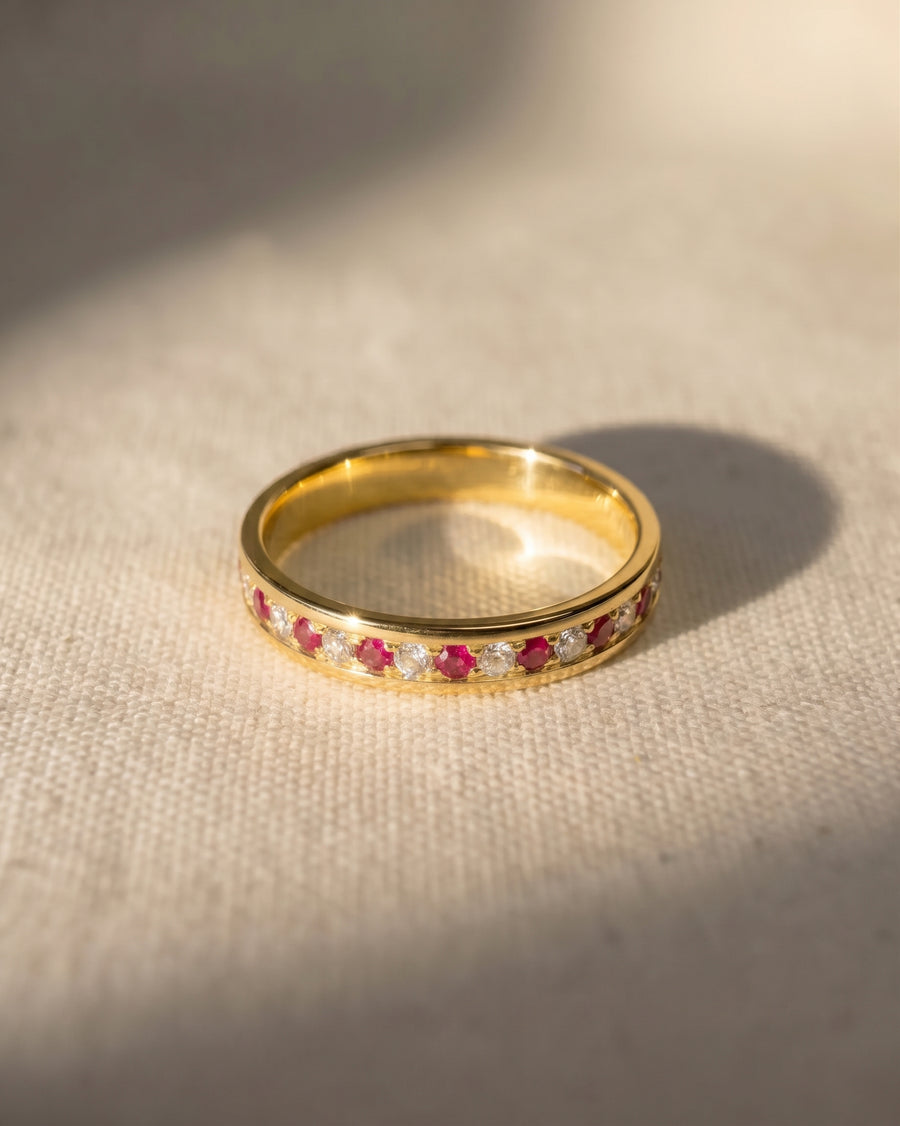Gold eternity ring with alternating ruby and diamond gemstones.