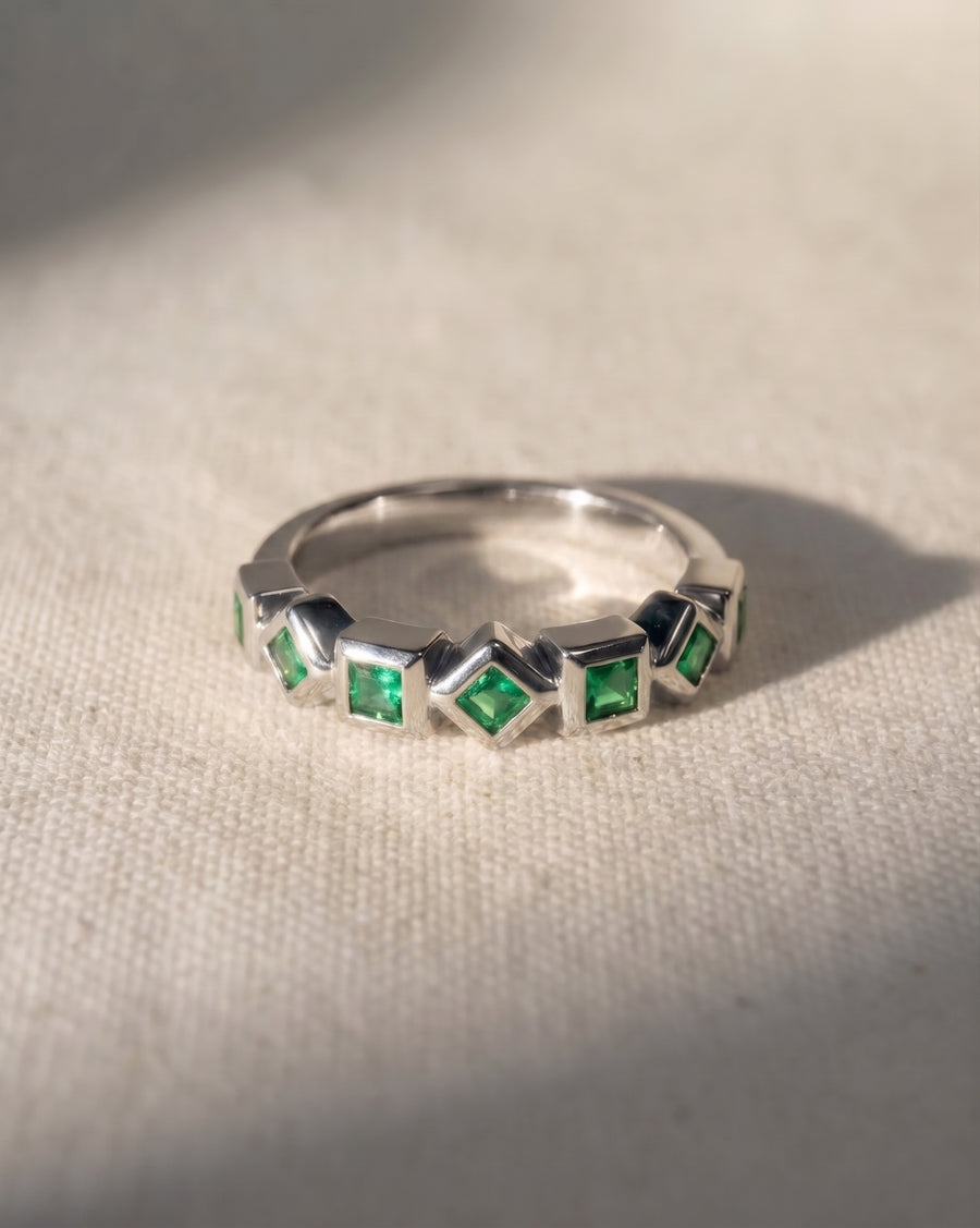 Platinum eternity ring with alternating square and diamond-shaped emeralds.