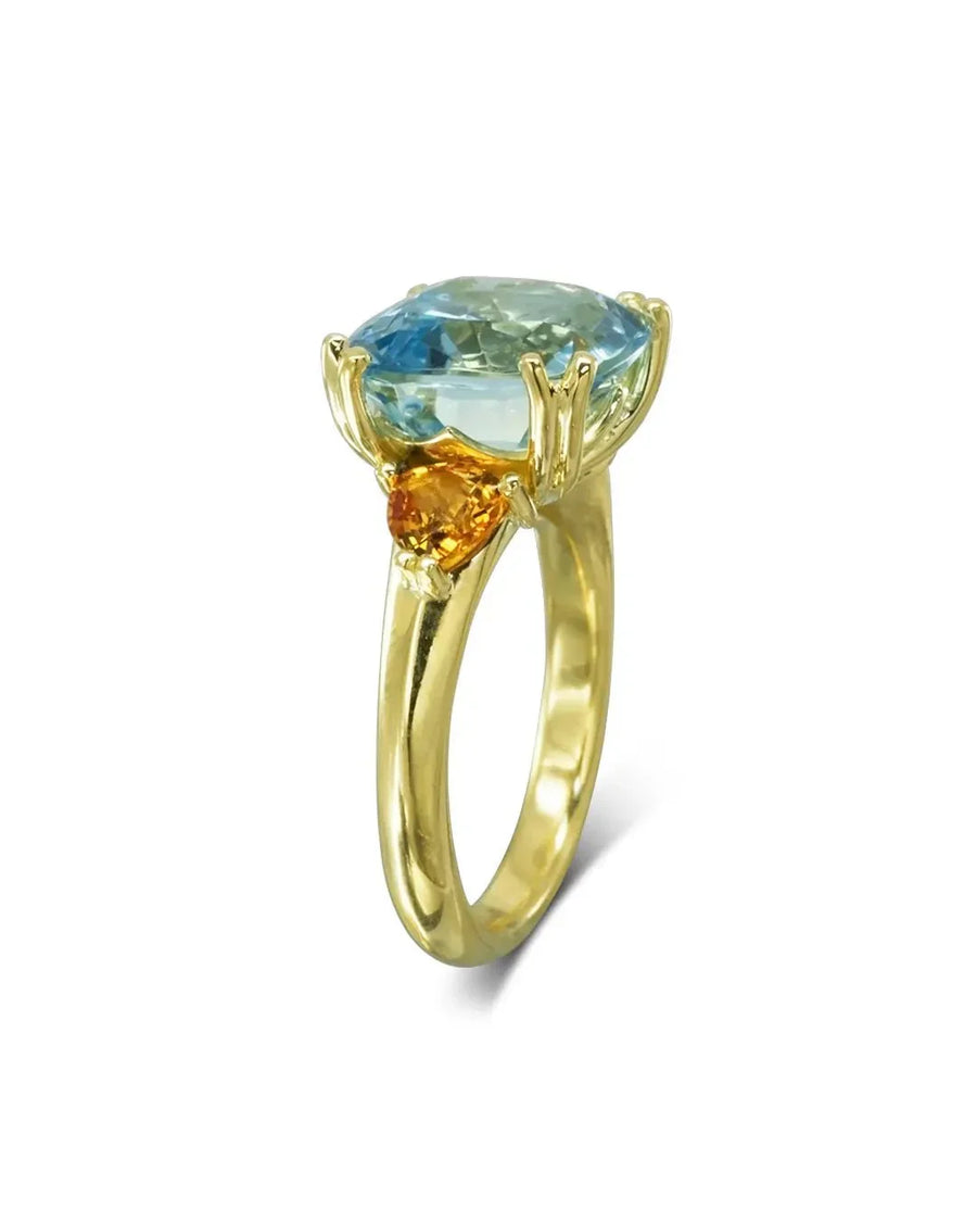 Gold dress ring with an oval aquamarine and two round orange sapphires.