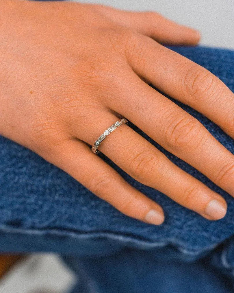 Platinum eternity ring with aquamarine and diamonds on hand, casual denim background