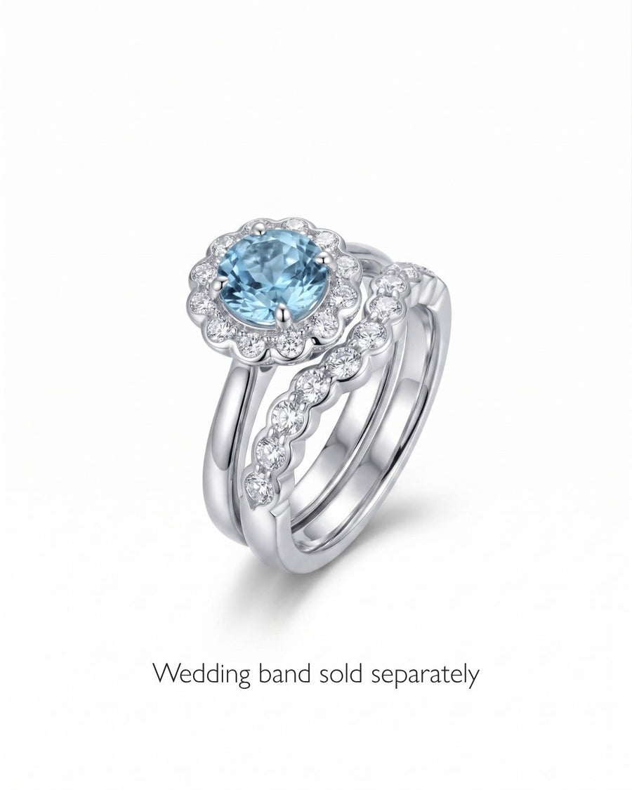 Silver ring with a round aquamarine surrounded by scalloped diamonds.