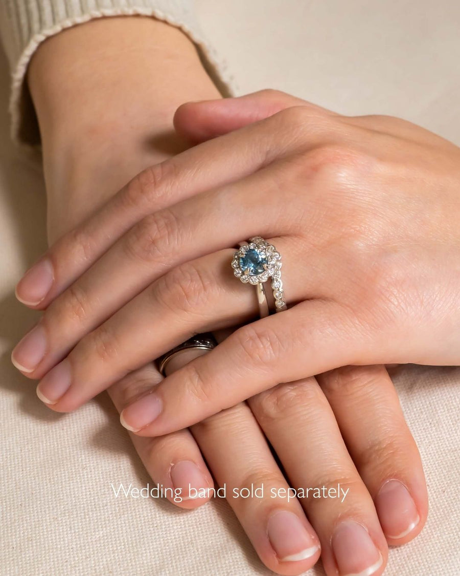 Aquamarine with scalloped diamonds cluster engagement ring on a hand.