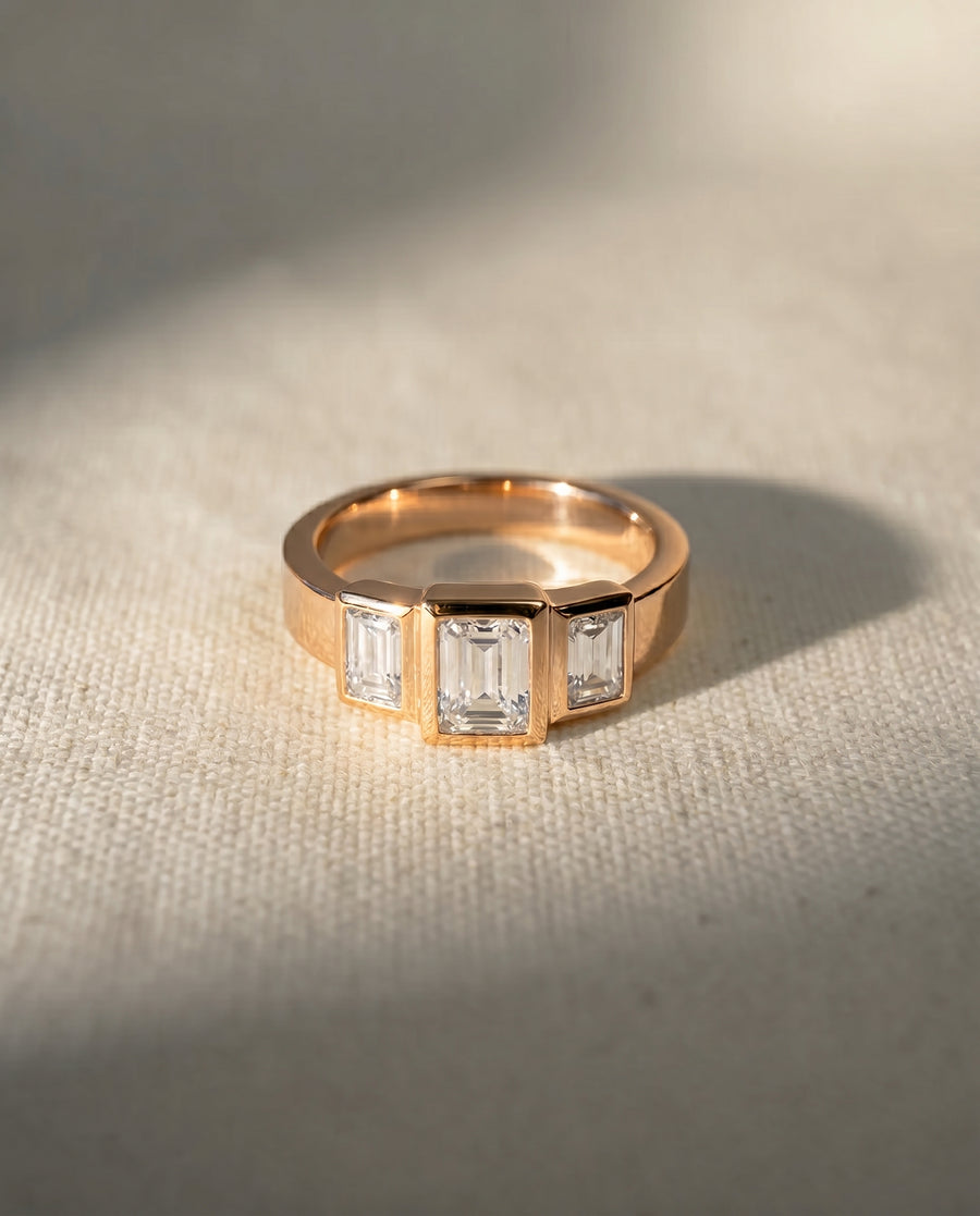 Rose gold ring with three emerald cut diamonds.