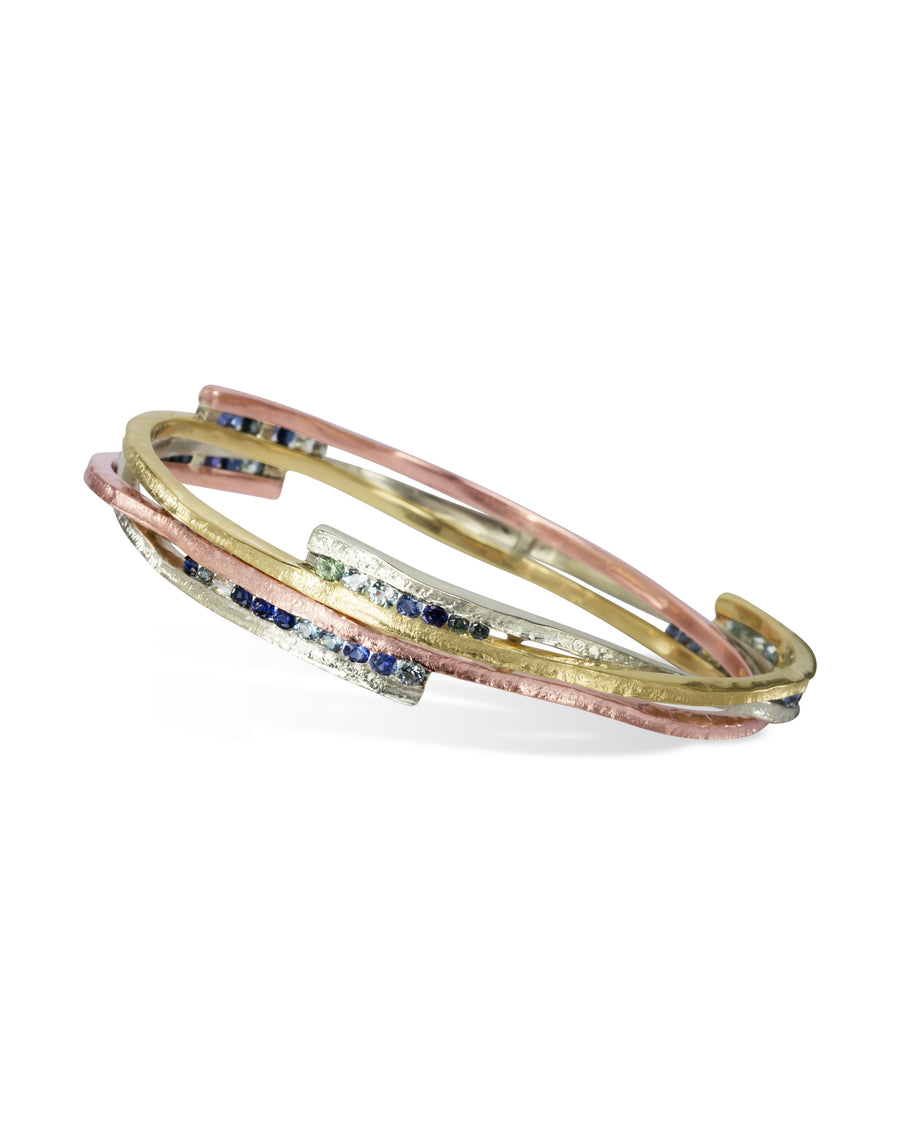 Asymmetric mixed metal bangle with sapphire gemstones.