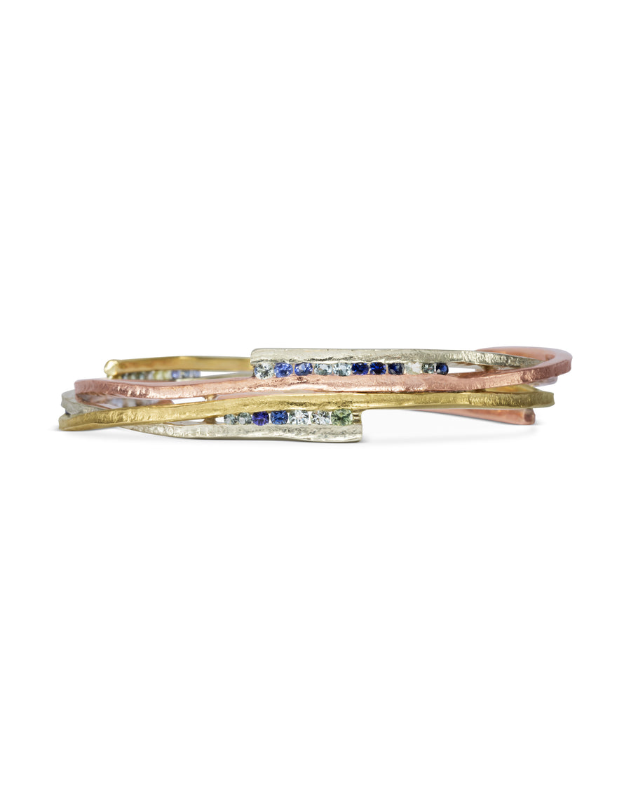 Asymmetric mixed metal bangle with blue sapphires.