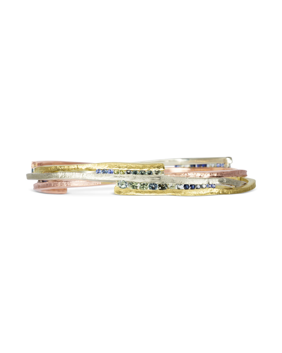 Asymmetric mixed metal bangle with sapphire gemstones.
