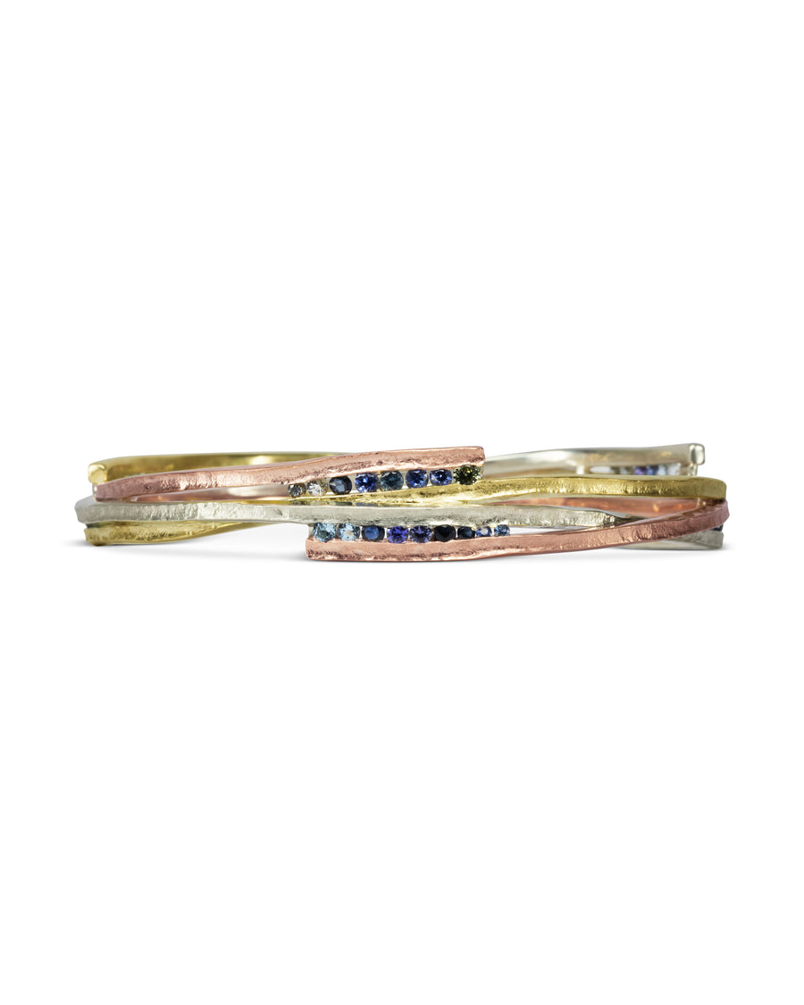 Asymmetric mixed metal bangle with blue sapphires.