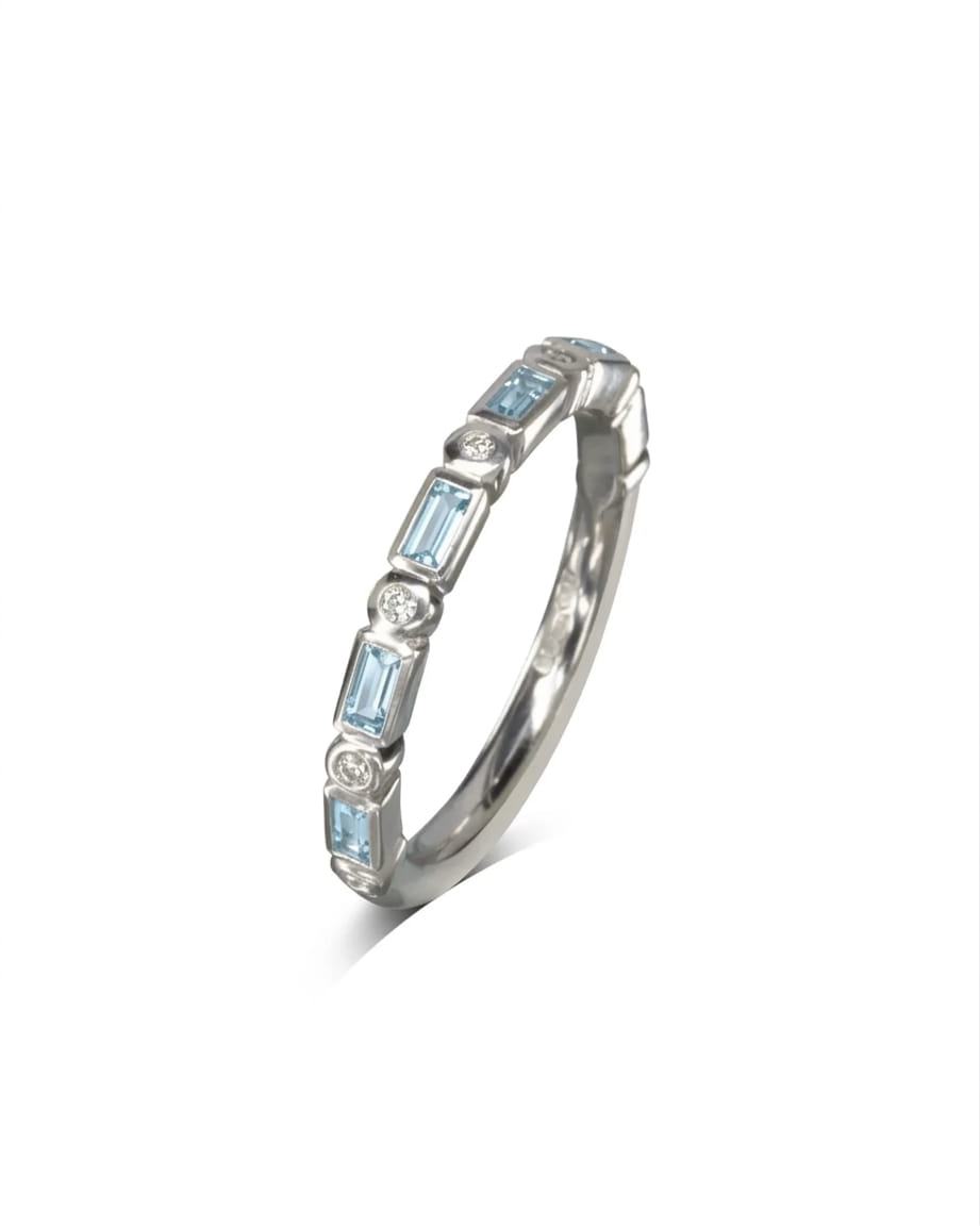 White gold eternity ring with baguette cut blue gemstones and round diamonds.