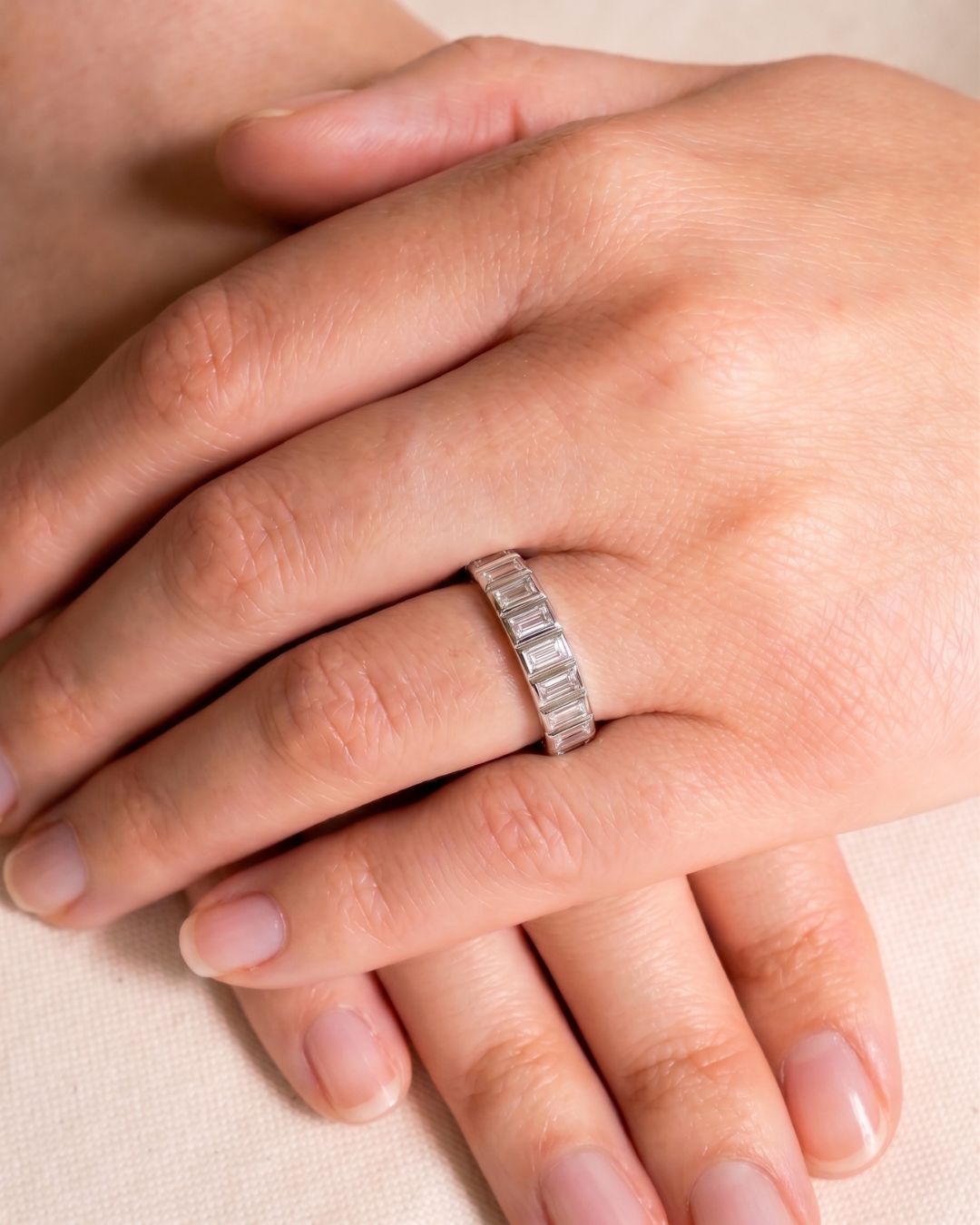 Platinum eternity ring with baguette diamonds on a hand.