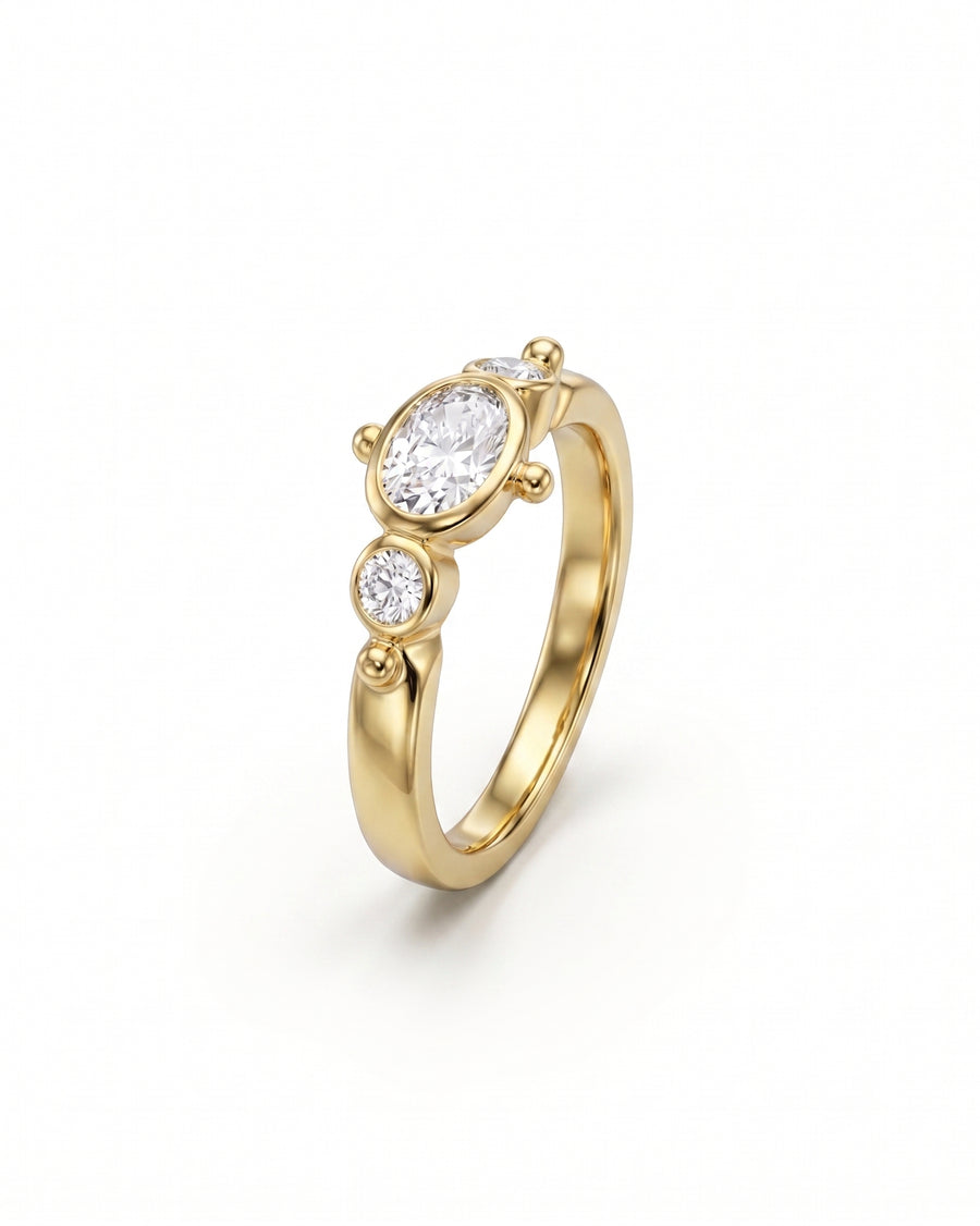 Gold ring with an oval diamond center and two round side diamonds.
