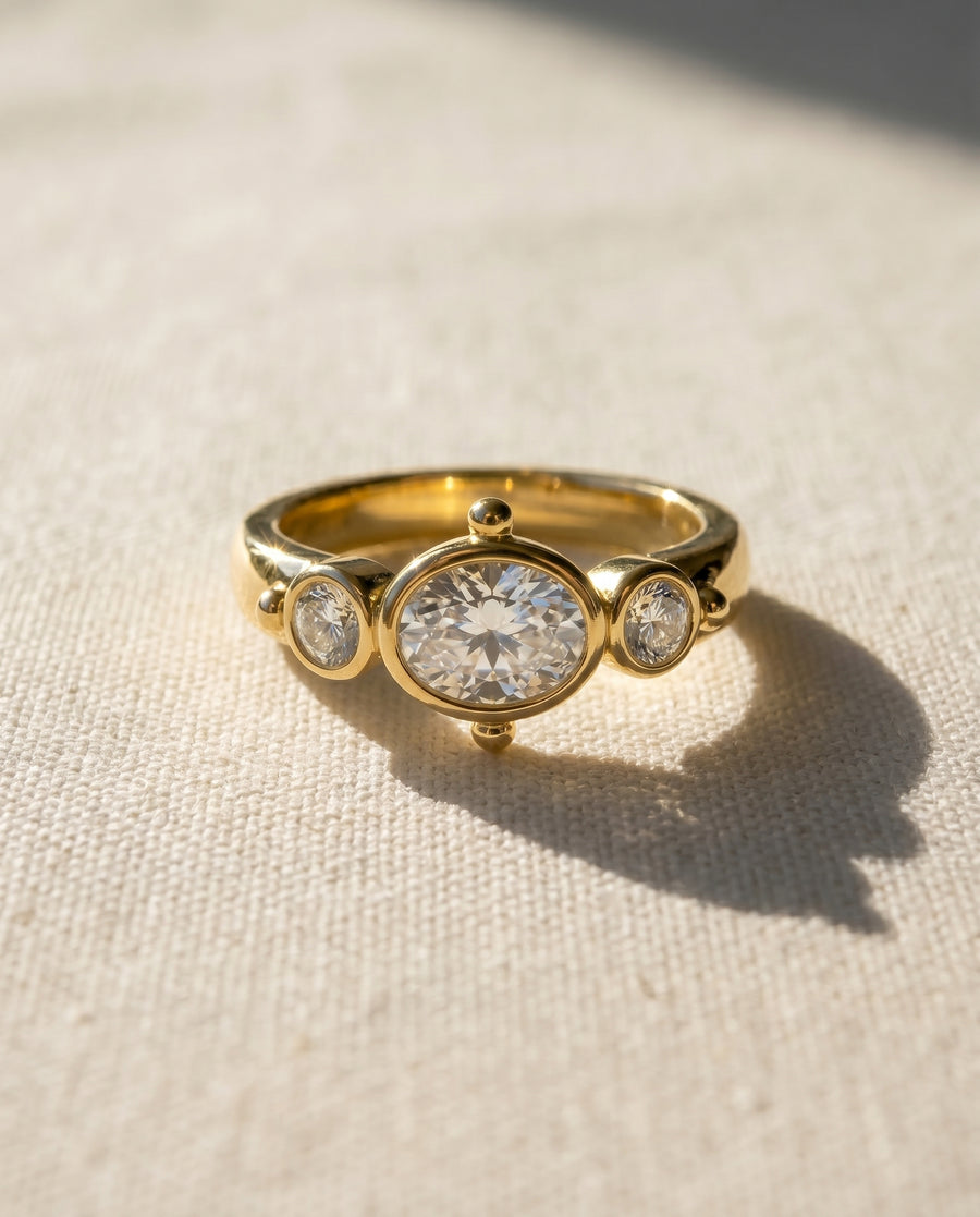 18ct yellow gold engagement ring with an oval diamond and two round diamonds.