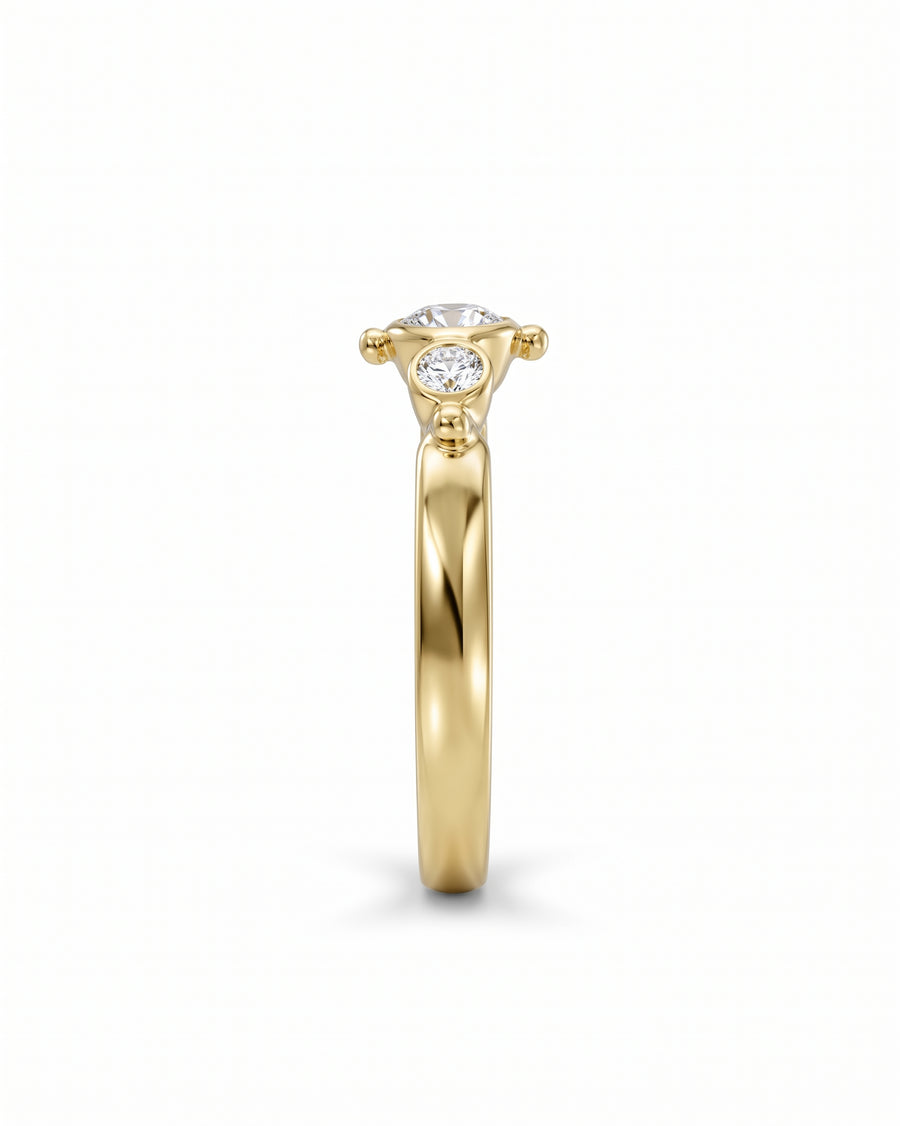 Yellow gold beaded oval diamond trilogy engagement ring.