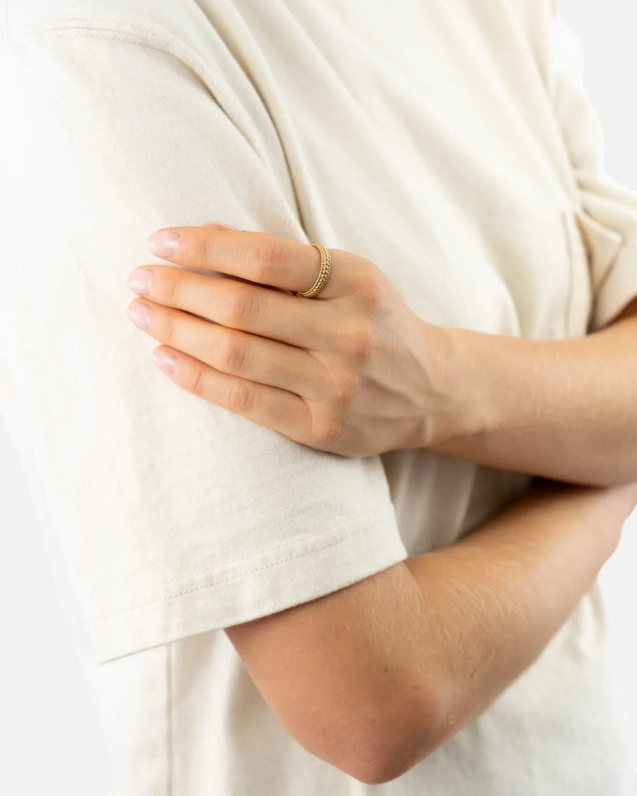 Elegant three-row beaded yellow gold ring worn on hand against a light shirt