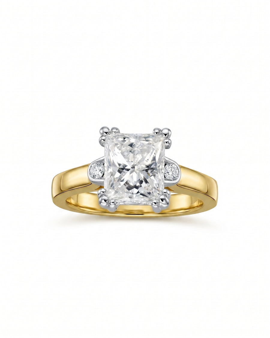 Gold engagement ring with a radiant cut diamond and two round side diamonds.