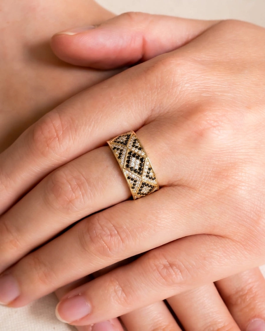 Gold eternity ring with black and white diamonds in a geometric pattern.