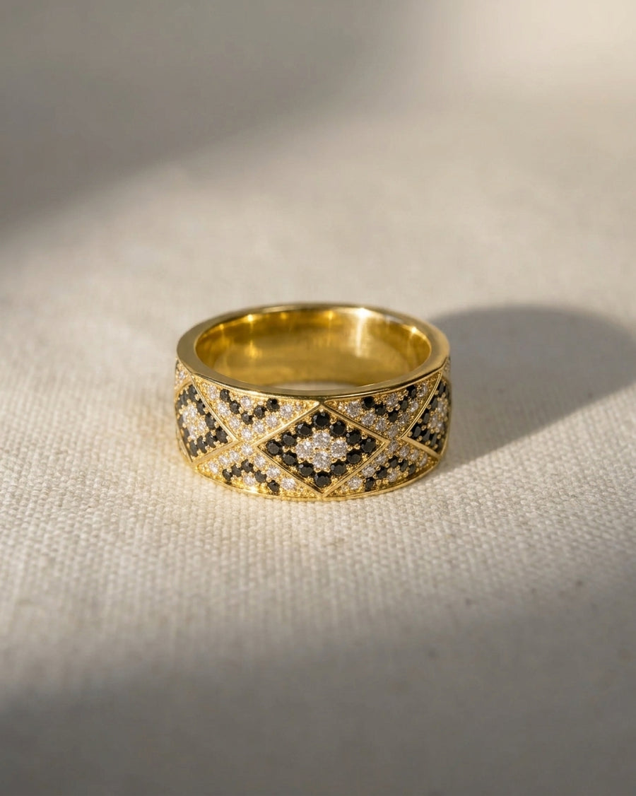 Gold eternity ring with black and white diamonds in a geometric pattern.