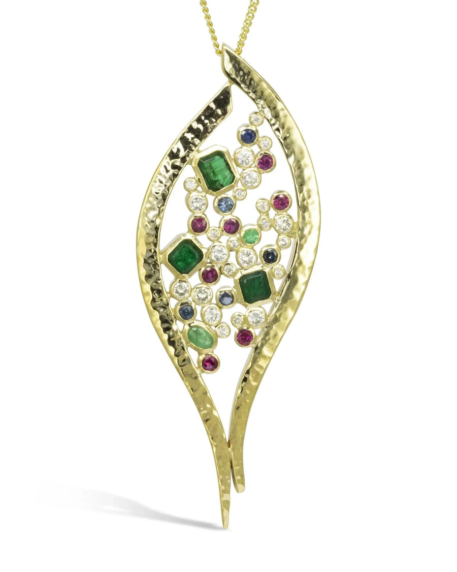 Forged gold pendant with hammered texture, set with diamonds, sapphires, rubies, and emeralds
