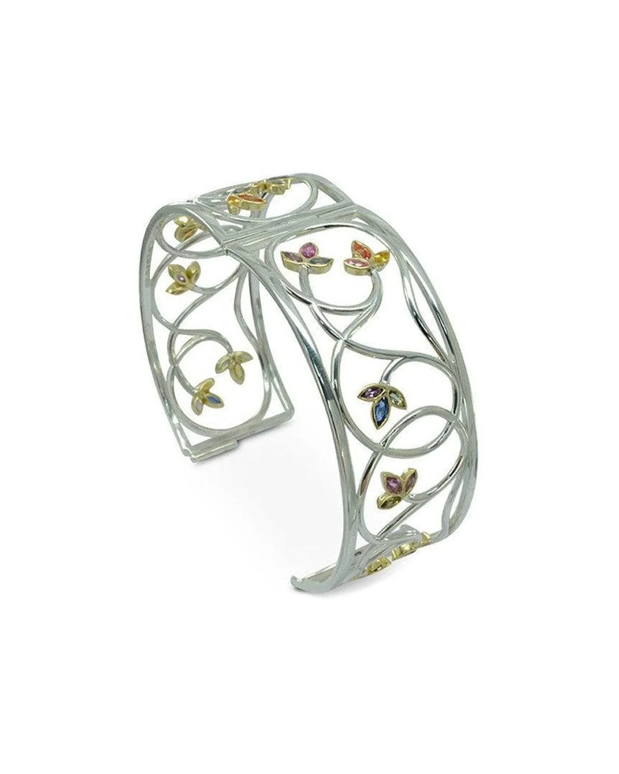Openwork gold bangle with floral motifs and sapphire gemstones, handmade, on white background
