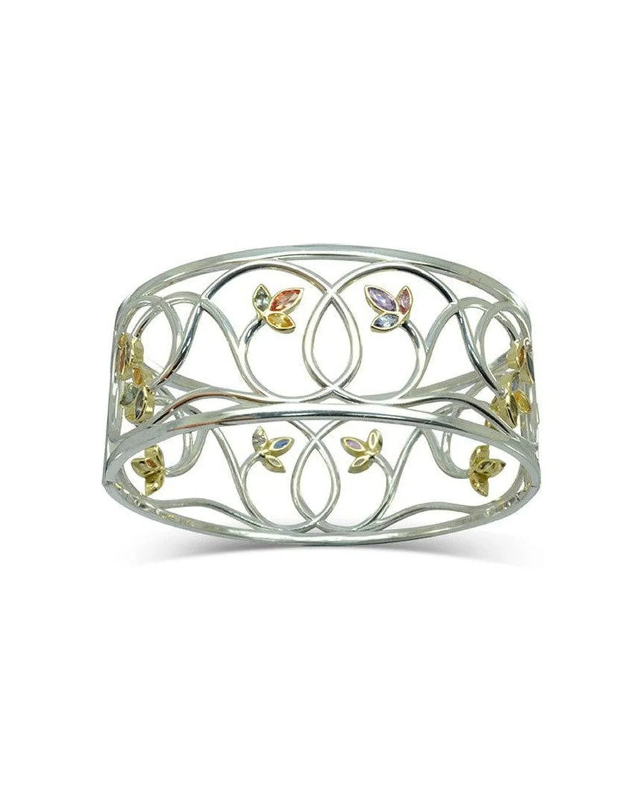 Handcrafted gold bangle with sapphire accents and intricate floral design on a white background