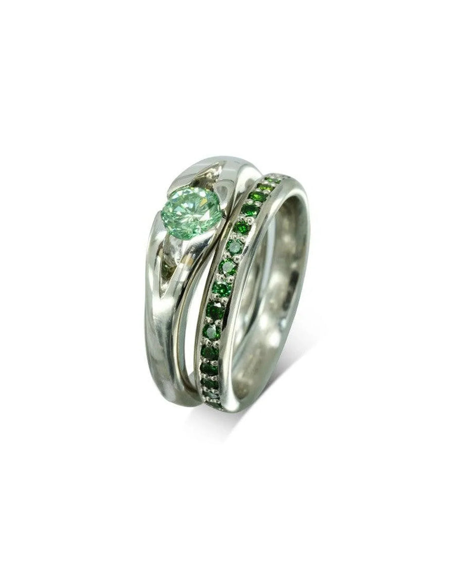 Platinum engagement ring with a green diamond and a platinum band with green diamonds.